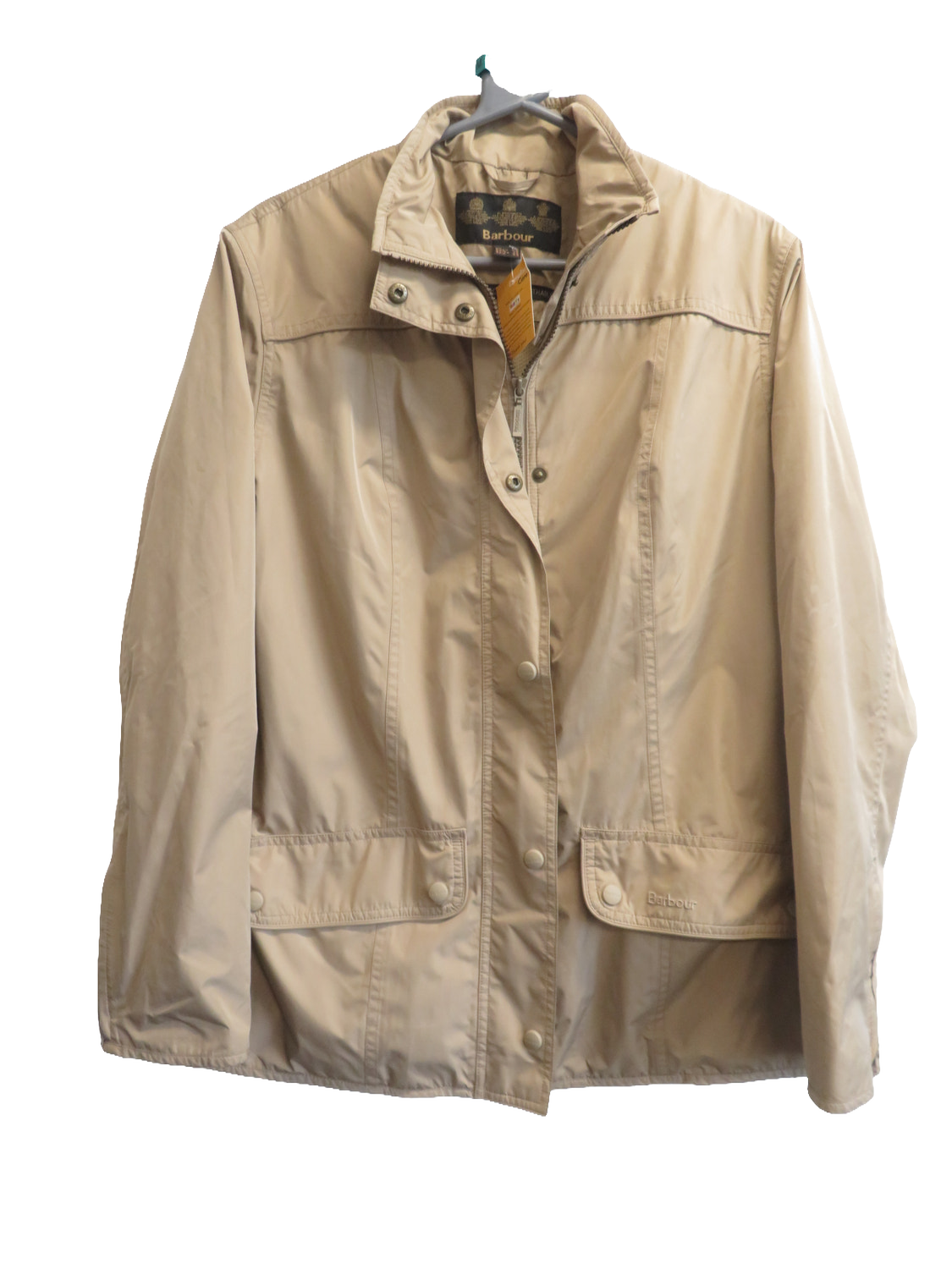 Front of the beige jacket on a hanger, showing the high collar, snap-fastened front, and two pockets with snap flaps.
