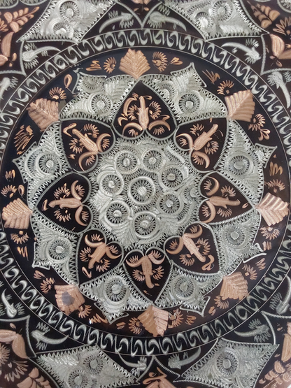 Close-up of the centre of the plate, showing fine etched rings and petal shapes in silver and copper, with some light wear on the copper areas.