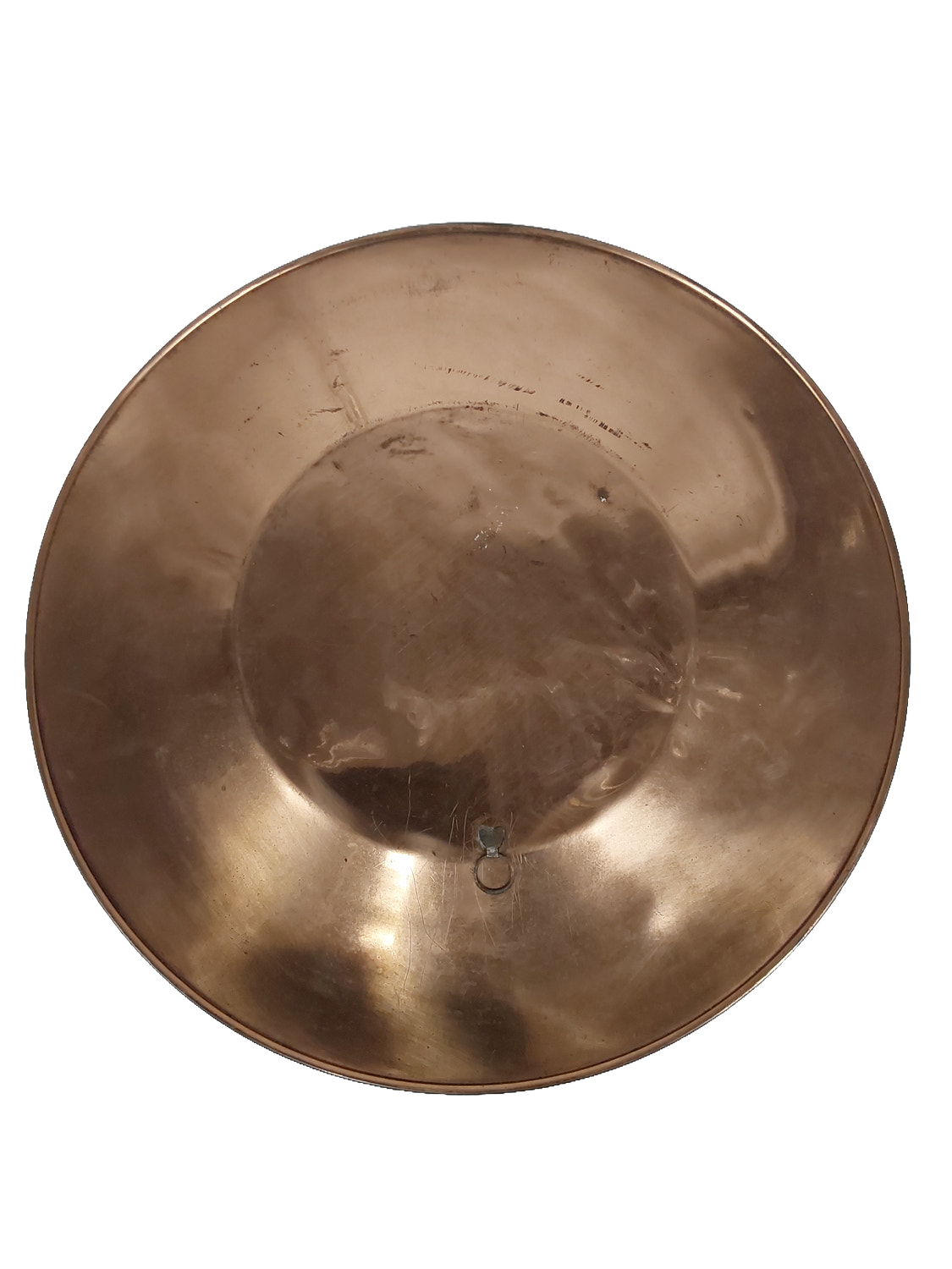 Back of the plate, plain polished copper with a small metal loop hanger fixed at the centre and a few light scratches visible.