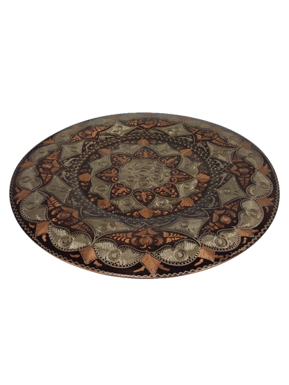 Front of the plate photographed at an angle, showing the curved surface and the etched pattern around the outer rim.