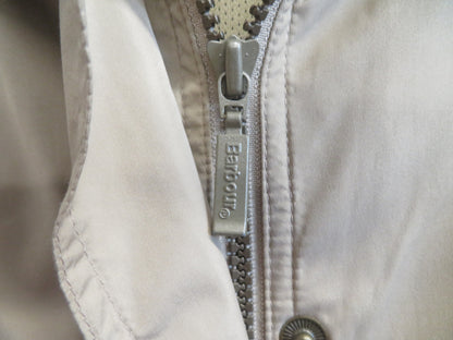 Close-up of the front zip with a metal pull tab marked Barbour, beside a snap fastener.