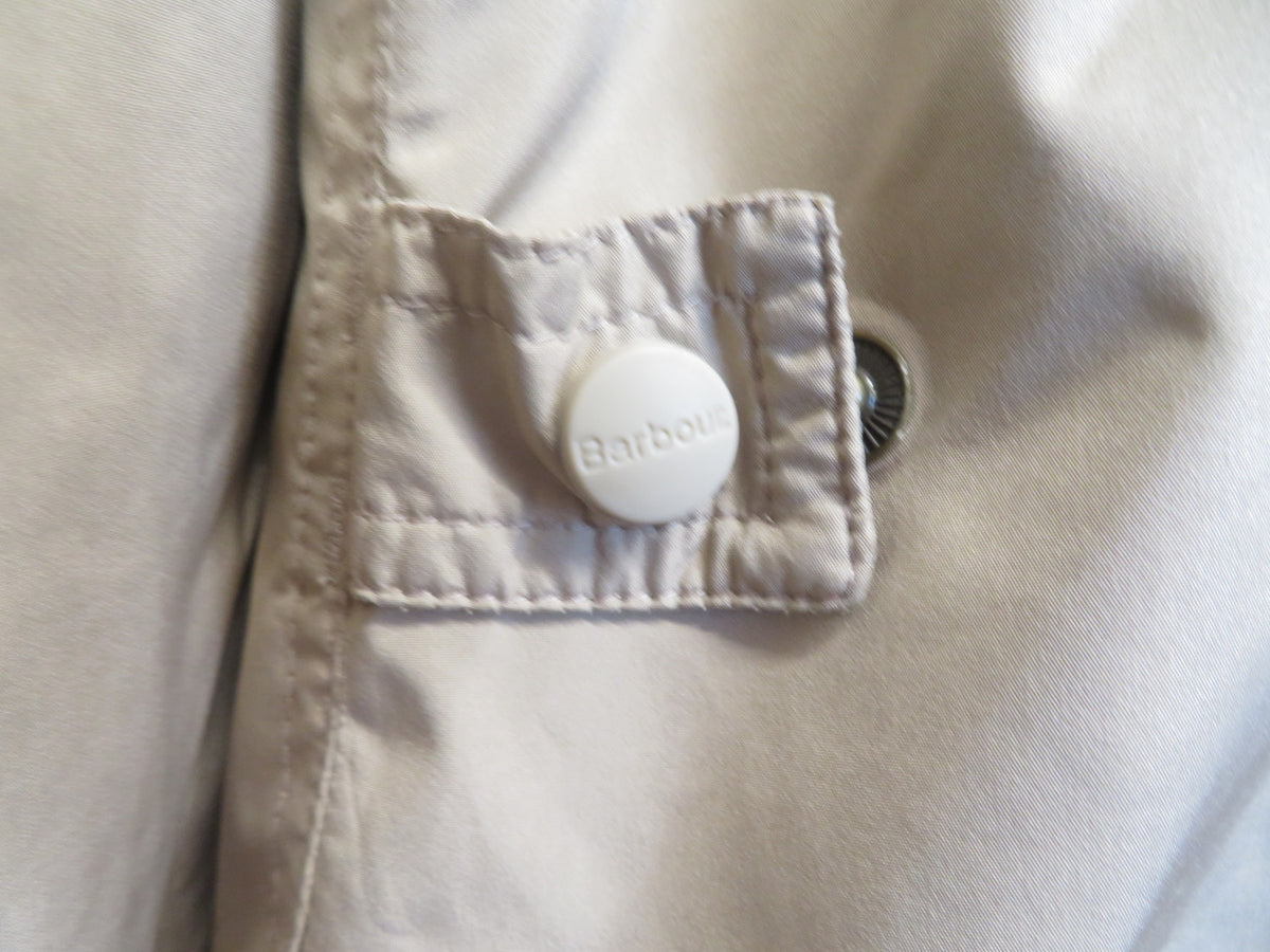 Close-up of a side pocket tab fastened with a white Barbour-branded snap button.
