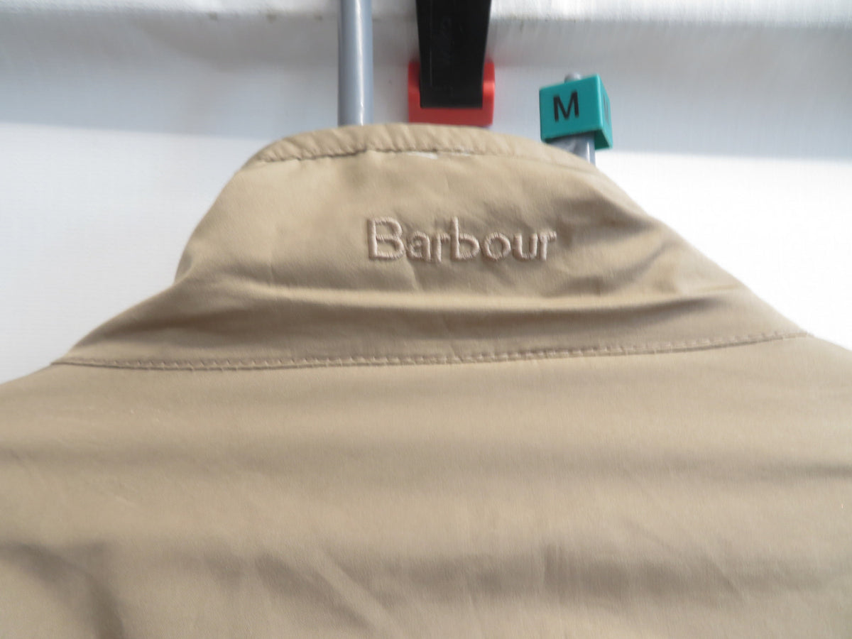 Back of the collar close-up showing the Barbour name embroidered in beige, with a green size tag reading M on the hanger.